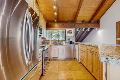 a kitchen with a stainless steel refrigerator and wooden cabinets at Northstar Condo with Forested Views in Truckee