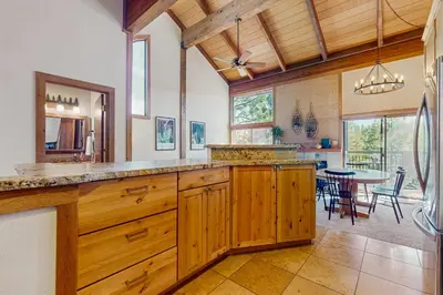 a kitchen with wooden cabinets and a dining room with a table at Northstar Condo with Forested Views in Truckee