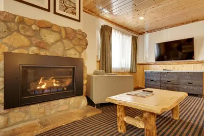 a living room with a fireplace and a table at 3 Peaks Resort & Beach Club in South Lake Tahoe