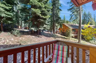 a wooden porch with a chair and a log cabin at Agate Road Retreat in Carnelian Bay