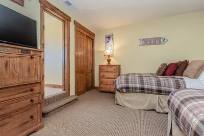 a bedroom with two beds and a flat screen tv at Lodges 1132 - 3 bedroom Townhome on Golf Course in Mammoth Lakes