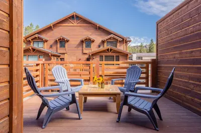 a wooden table and chairs on a deck with a house at Mountainside 4 in Mammoth Lakes