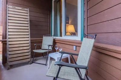two chairs and a table on a porch with a window at Juniper Springs Lodge #238 in Mammoth Lakes
