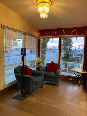 a room with two chairs and windows with christmas decorations at La Plaza Inn in Los Banos