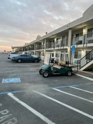 a golf cart parked in a parking lot in front of a building at La Plaza Inn in Los Banos