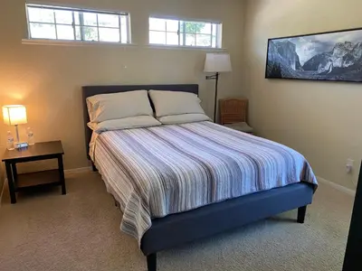 a bedroom with a bed and a table and two windows at Oak Retreat by Yosemite National Park in Coarsegold