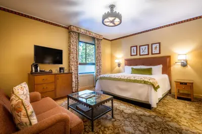 a bedroom with a bed and a couch and a tv at The Ahwahnee in Yosemite Village