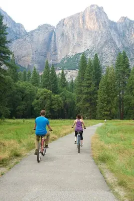 a man and a girl riding bikes down a path at The Ahwahnee in Yosemite Village