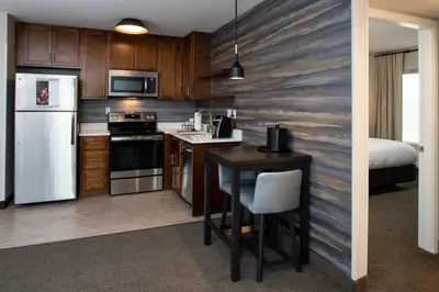a kitchen with a refrigerator and a table and a bed at Residence Inn Visalia in Visalia