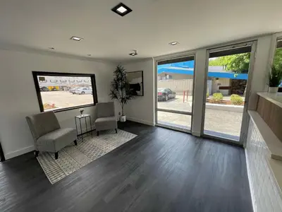 a living room with two chairs and sliding glass doors at The Midtowner Hotel, SureStay Collection by Best Western in Sacramento
