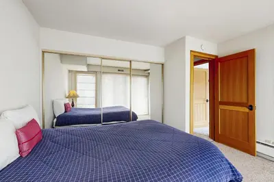 a bedroom with two beds with blue sheets and a door at Scott Peak Views in Alpine Meadows