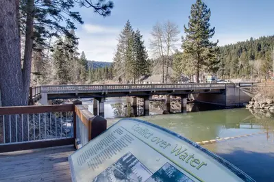 a bridge over a river with a sign in the foreground at Scott Peak Views in Alpine Meadows