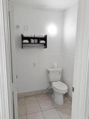 a bathroom with a toilet and a shelf on the wall at Dream Inn in Fresno
