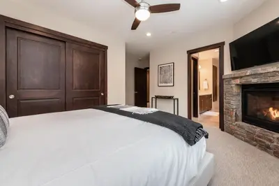 a bedroom with a white bed and a fireplace at Mountainside 15 in Mammoth Lakes