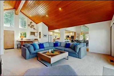 a large living room with blue couches and a table at Sleek Hill Haven with Martis Valley Views in Polaris