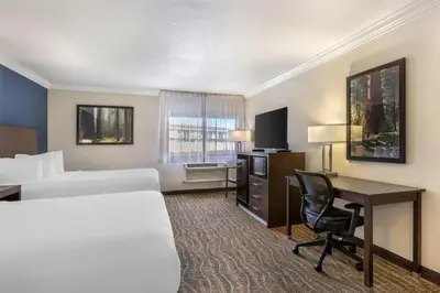 a hotel room with two beds and a desk at Best Western Town & Country Lodge in Tulare