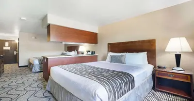 a hotel room with a large bed and a lamp at SureStay Plus Hotel by Best Western Rocklin in Rocklin