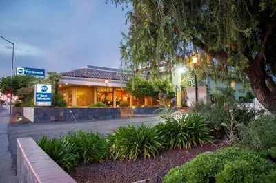 a building on a street with a bench in front at Best Western Village Inn in Fresno