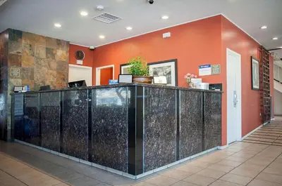 a lobby with a reception counter and orange walls at Best Western Village Inn in Fresno