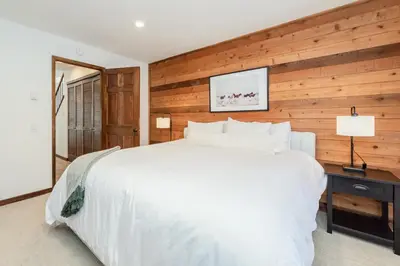 a bedroom with a white bed and a wooden wall at Snowflower 12 in Mammoth Lakes