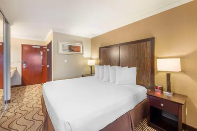 a hotel room with a large bed with white sheets at Best Western Plus Orchid Hotel & Suites in Roseville