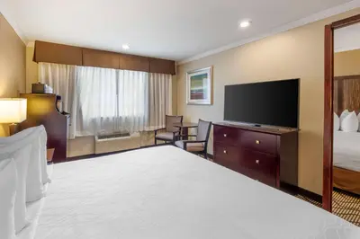 a hotel room with a bed and a flat screen tv at Best Western Plus Orchid Hotel & Suites in Roseville
