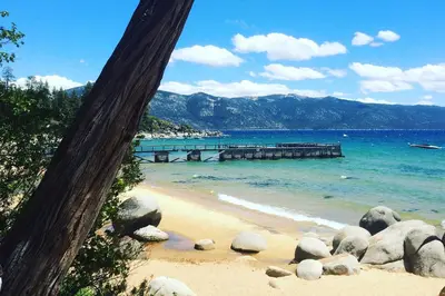 a beach with rocks and a pier in the water at Boutique and Artsy Log Cabin in North Lake Tahoe! in Kings Beach