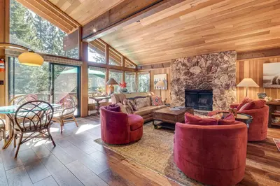 a living room with red chairs and a stone fireplace at Family-Friendly Truckee Cabin Near Ski Shuttle! in Truckee