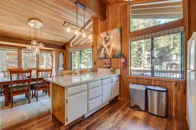 a kitchen with wooden walls and a dining room with a table at Family-Friendly Truckee Cabin Near Ski Shuttle! in Truckee