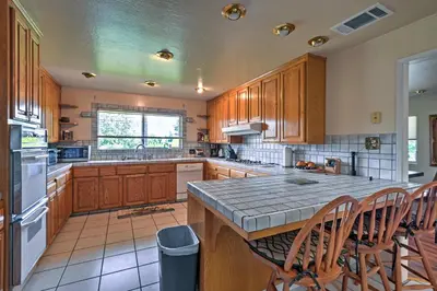 a large kitchen with wooden cabinets and a counter top at 7 Mi to Dtwn Gilroy Spacious Home on 20 Acres! in Gilroy