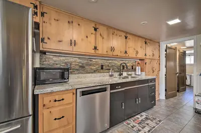 a kitchen with stainless steel appliances and wooden cabinets at Historic Mariposa Stagecoach Stop with Gas Fire Pit! in Mariposa