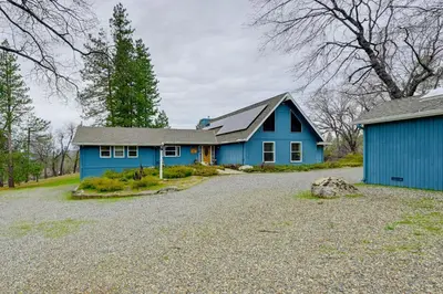 a blue house with a gravel driveway in front of it at 7 Mi to Bass Lake! Spacious Mudge Ranch Retreat in Coarsegold