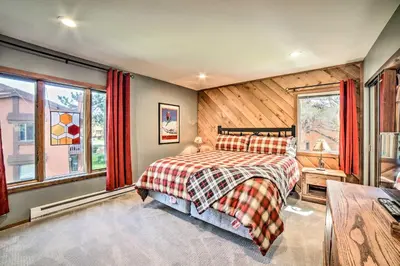 a bedroom with a bed and windows with red curtains at Renovated Mammoth Lakes Retreat with Private Balcony in Mammoth Lakes