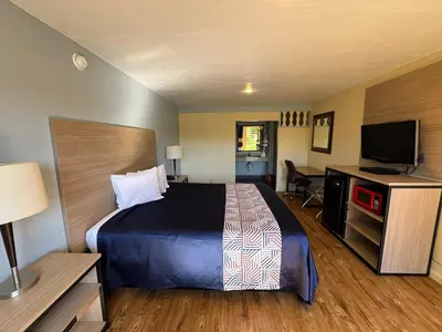 a hotel room with a bed and a flat screen tv at Discovery Inn in Modesto