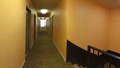 a hallway with a long corridor with yellow walls at Discovery Inn in Modesto