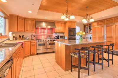 a kitchen with wooden cabinets and a island with bar stools at Mtn and Lake Views Incline Village Ski Chalet in Incline Village