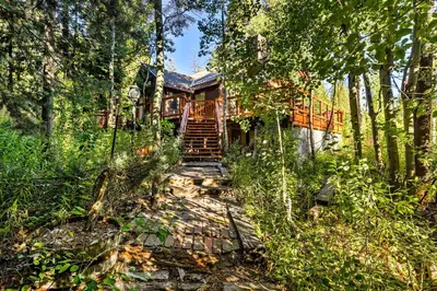 a house in the woods with stairs leading to it at Rustic Riverfront Truckee Cabin with Deck and BBQ in Truckee
