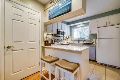 a kitchen with white cabinets and a counter with stools at 1 Mi to Diamond Peak Ski Resort Condo with Pool in Incline Village