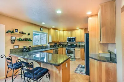 a large kitchen with wooden cabinets and a large island at 4 Mi to Pine Lake Hathaway Pines Cabin with Deck in Hathaway Pines