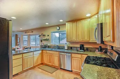 a kitchen with wooden cabinets and a stove top oven at 4 Mi to Pine Lake Hathaway Pines Cabin with Deck in Hathaway Pines