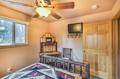 a bedroom with a ceiling fan and a bed and a tv at 4 Mi to Pine Lake Hathaway Pines Cabin with Deck in Hathaway Pines