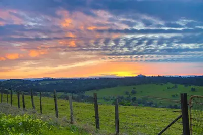 a fence in a field with the sunset in the background at Working Vineyard and Private Pool Villa in Plymouth in Plymouth