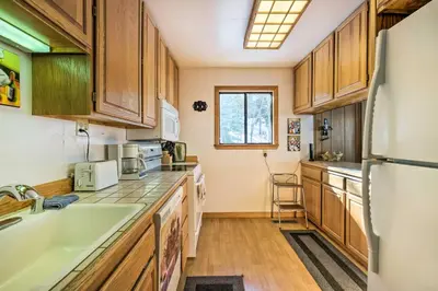 a kitchen with wooden cabinets and a white refrigerator at Near Hiking and Skiing Bear Valley Cabin! in Tamarack