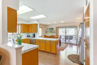 a large kitchen with wooden cabinets and a large window at Mountain Paradise about 1 Mile to Pine Mountain Lake! in Groveland