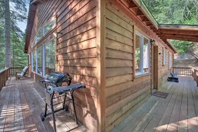 a front porch of a wooden cabin with a grill on it at Walk to Big Trees State Park Cabin with Deck! in Dorrington