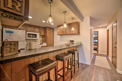 a kitchen with a bar with stools in it at Mammoth Lakes Condo, Walk to Shuttle and Village in Mammoth Lakes