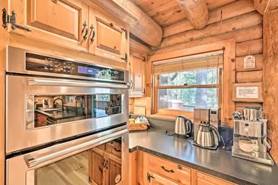 a kitchen with wooden cabinets and a stainless steel appliance at 5 Mi to Hiking Custom Cabin with Deck in Arnold! in Arnold