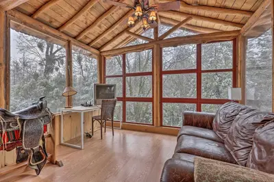 a living room with a couch and a tv and windows at Creekside Cabin 8 Mi to Kings Canyon National Park in Miramonte