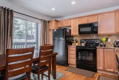 a kitchen with a table and a black refrigerator at Sierra Park Villas N-#66 in Mammoth Lakes