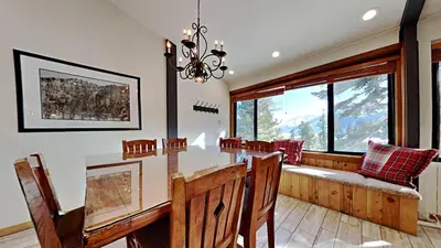 a dining room with a table and chairs and windows at Spectacular 3 Bedroom Townhome with Pool in Mammoth Lakes